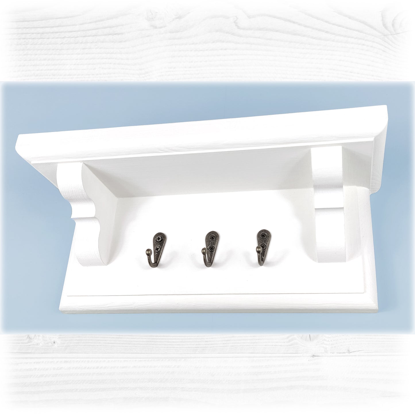 A white wooden floating key rack featuring a shelf with bronze colour key hooks on a blue background